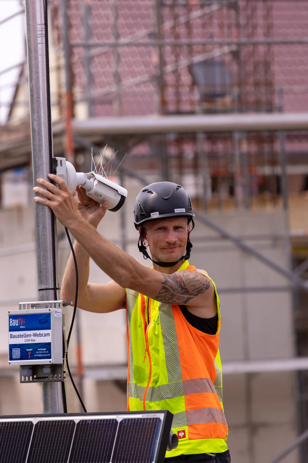 Technician installing a construction camera on a mast